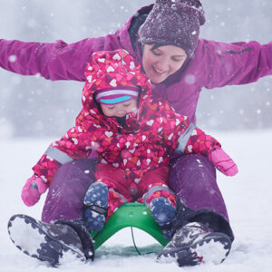 Mom and child on a sled in the snow